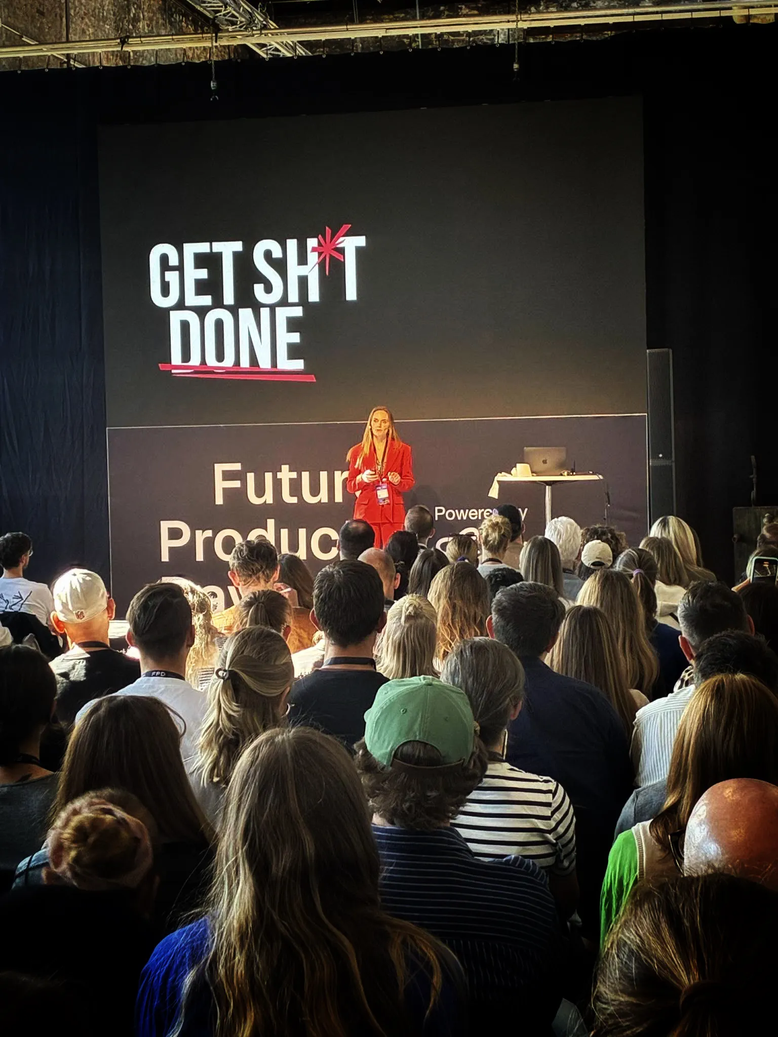 Oplæg fra scenen foran et fuldt publikum med “Get Sh*t Done” på storskærmen