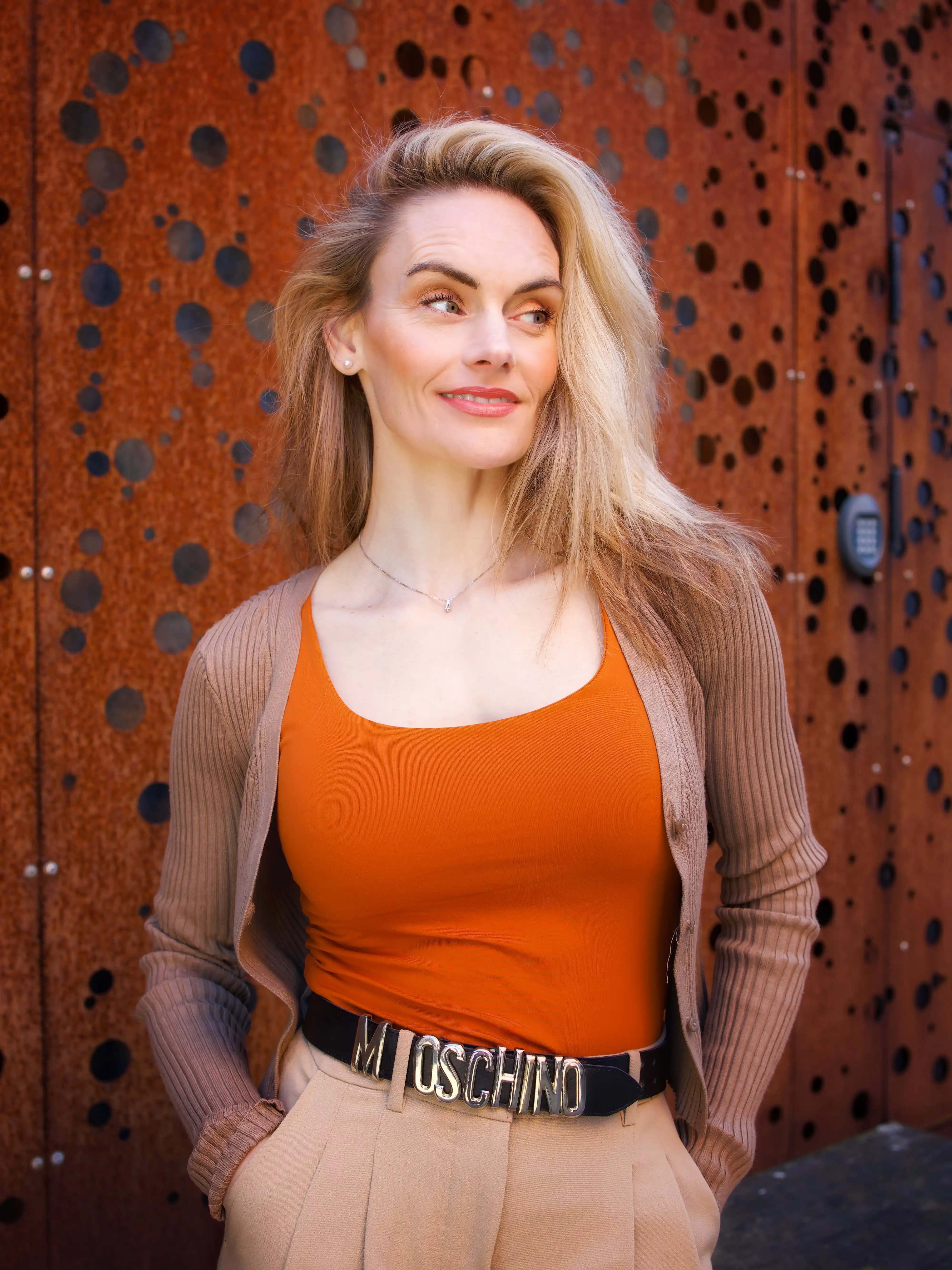 Marlene Gyldenberg i orange top foran en rustrød stålfacade